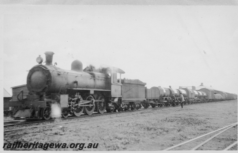 P02937
E class steam locomotive hauling a mixed goods train including tankers, roof of station building in the background, KL line.
