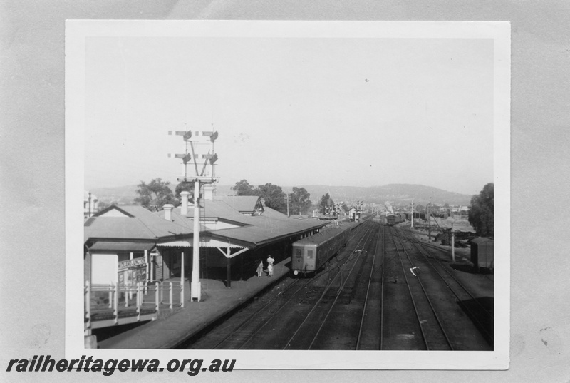 P03080
ADU class diesel railcar trailer with end of train disc, bracket signals, station buildings, passenger platform, nameboard, water column, signal box (Cabin 'B'), sidings and tracks, Midland Junction, view from footbridge looking east, ER line.
