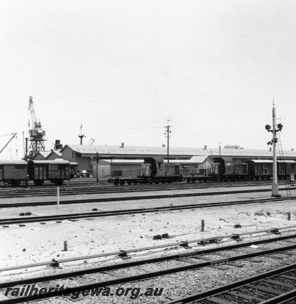 P03162
B class 1606 and B class 1607 diesel hydraulic shunting locomotive, signals, signal rodding, wharf crane, E shed wharf shed, tracks, brakevans, covered vans, Fremantle, ER line.
