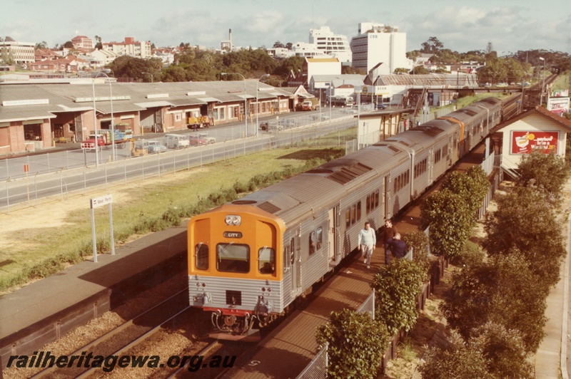 P03189
ADL/ADC diesel railcar set, front and side view, small passenger shelter and station building, footbridge, nameboard, metropolitan markets in the background, West Perth, ER line.
