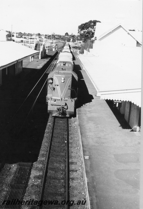 P03197
A class 1502 diesel locomotive, front view, goods train, foot bridge, signals, station buildings, passenger platforms, signal rodding, Claremont, ER line.
