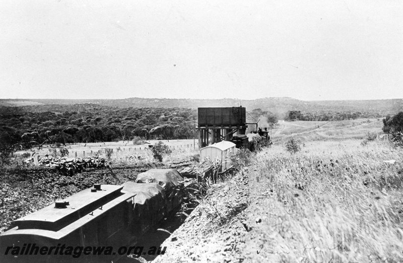 P03272
Steam locomotive taking on water at Grant's, goods train, water tower with 25,000 gal. cast iron tank, water column, NR line, c1900.
