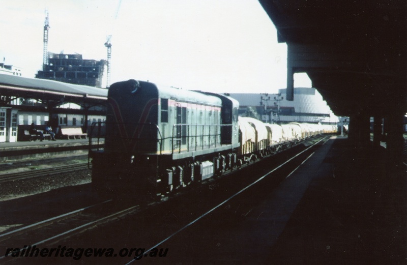 P03473
C class 1702 diesel locomotive, front and side view, on superphosphate train from Kwinana, semaphore signals, Perth, ER line.
