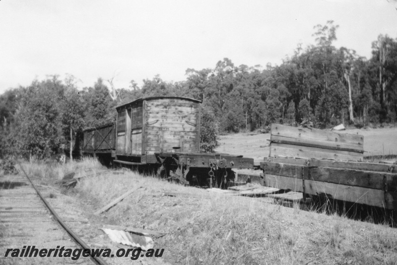 P03490
Timber line rolling stock on siding top of yard various wagons, Bush in back ground
