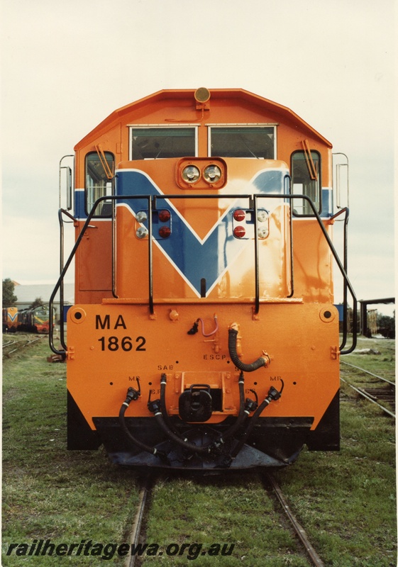 P03554
MA class 1862 diesel locomotive, front view, in orange livery, X class diesel in the background in green livery, c1970s.
