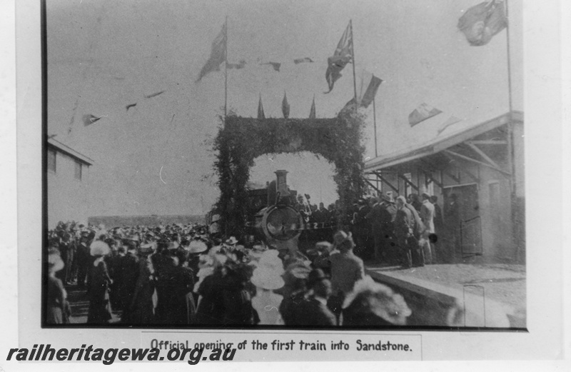 P03567
Unknown class of loco, station building, Sandstone, NR line, large crowd gathered to watch the train pass through an archway to mark the opening of the line, the line closed in 1949
