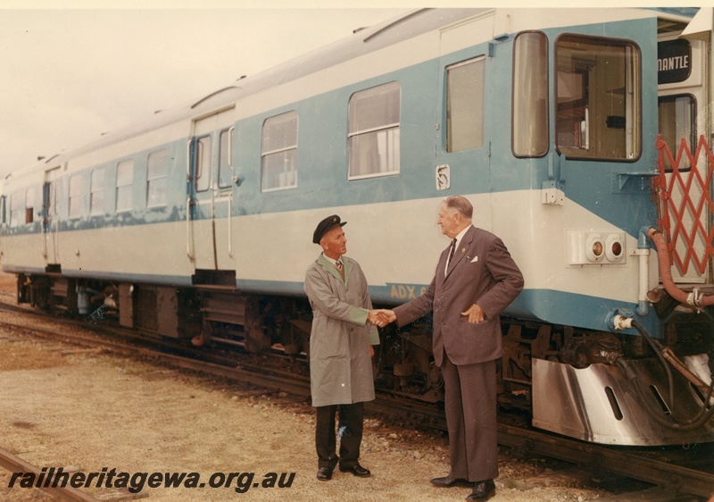 P03801
ADX class 670, blue and white livery, side and end view, two men shaking hands at track side, ER line
