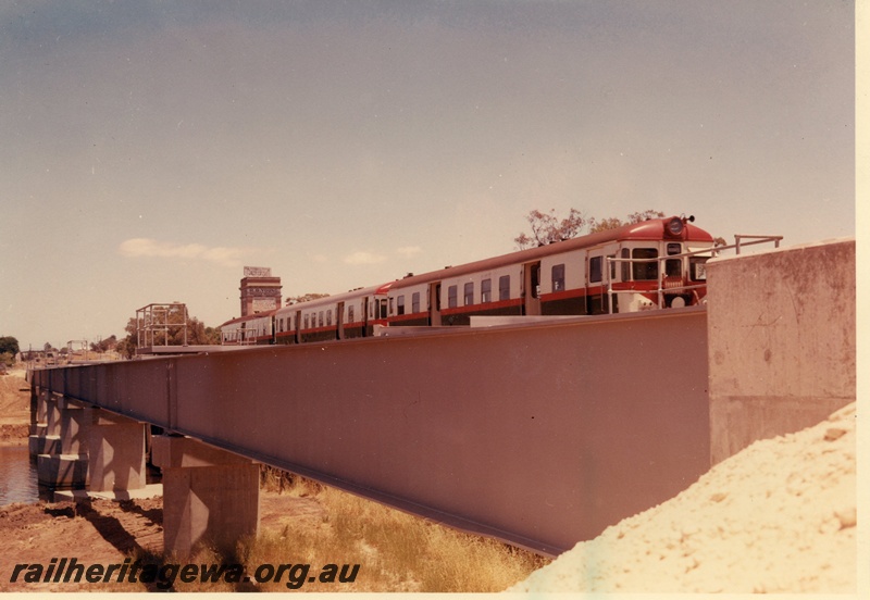 P03887
ADG class railcar set on Guildford bridge, red, green and white livery, front and side view.
