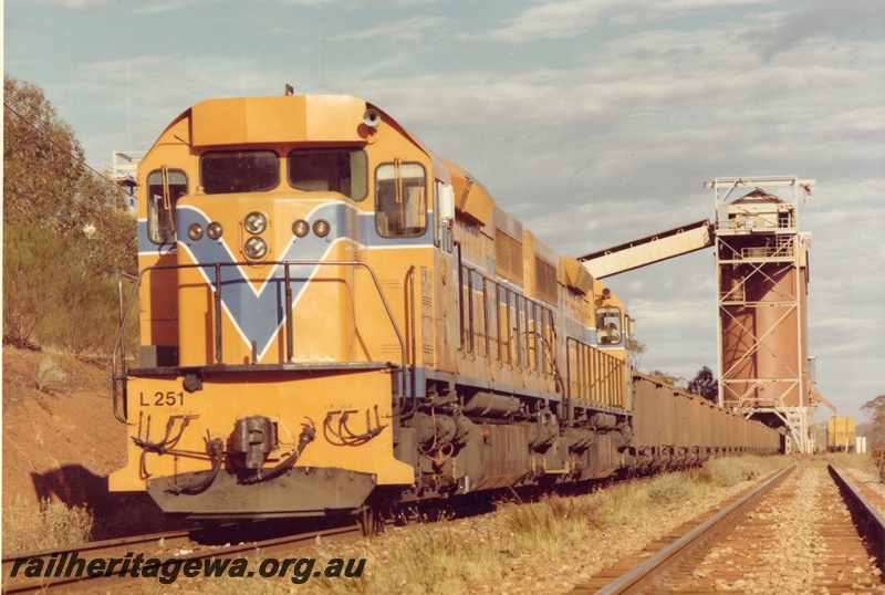 P03923
L class 251 standard gauge diesel locomotive, front and side view, in Westrail orange livery double heading another diesel locomotive in Westrail orange livery, on iron ore train, WO class iron ore wagons, loading at Koolyanobbing, standard gauge line. 
