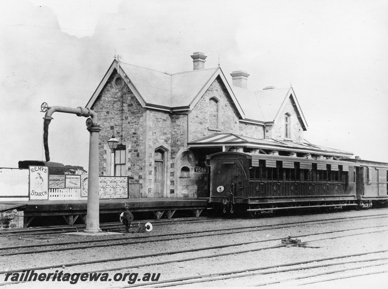 P04376
Station building, trackside view of York station building in unpainted bare stone, AD class carriage and clerestory roofed brakevan at the platform, old style water column, points indicator, cheese knob, York, GSR line.
