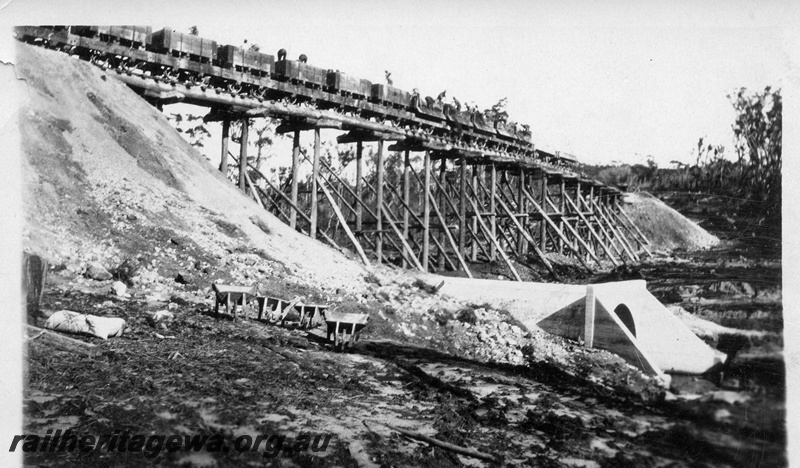 P04387
5 of 5, Trestles (30ft high) used for embankment construction, showing men shovelling fill material out of wagons over the side of the trestle and the culvert under the bank, Denmark-Nornalup railway construction, c1928-29.
