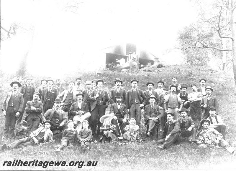 P07126
Group photo of the loco staff, Midland Junction, taken on the embankment behind the loco shed, Centre of the photo is Mr Frank Cook, loco foreman with his two daughters, J class loco in the loco shed in the background
