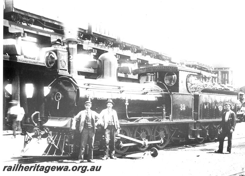 P07414
G class 32, 2-6-0 steam locomotive, in original condition,front and side view, elevated coal stage, water tower and shed in the background, workers standing in front of the loco, Kalgoorlie, EGR line, c1893-94. Same as  P02822 & P07564 
