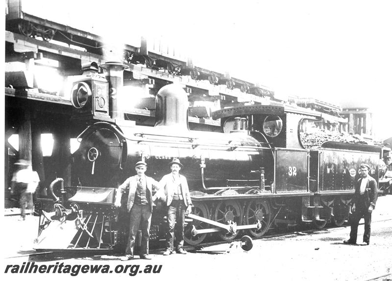 P07414
G class 32, 2-6-0 steam locomotive, in original condition,front and side view, elevated coal stage, water tower and shed in the background, workers standing in front of the loco, Kalgoorlie, EGR line, c1893-94. Same as  P02822 & P07564 
