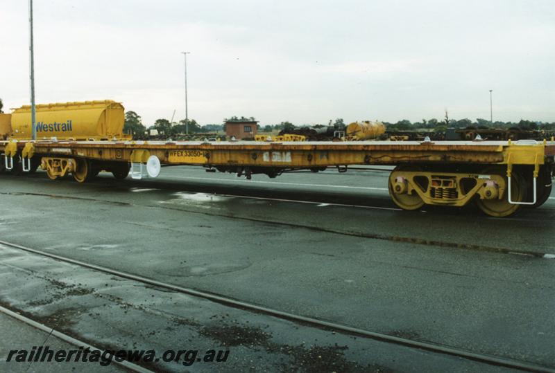 P08942
3 of 3 views of WFEX class 33050-M standard gauge flat wagon with end bulkheads removed, new steps, brake wheels and deck anchor points fitted. Tank from JG class tank wagon in background.
