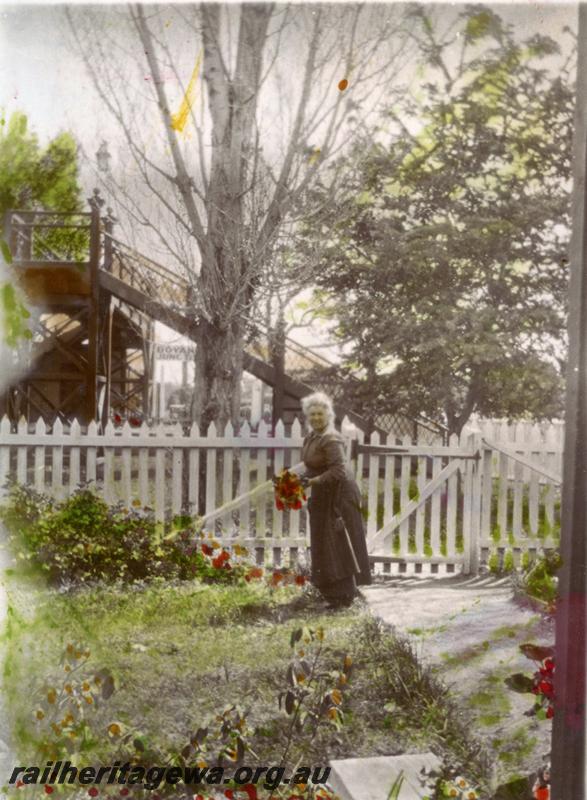 P09350
Mrs Copley, wife of the stationmaster in the front garden on the stationmasters house, the footbridge and the station nameboard, 