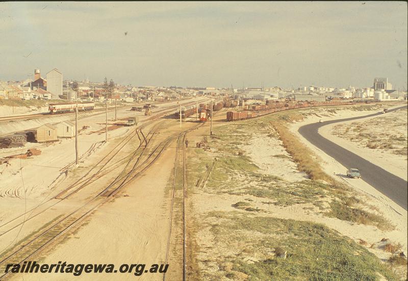 P09802
Leighton Yard, overall view, railcar set on down main, Y class shunting in yard, Y class in distance on Rocky Bay line, car carrying wagons in yard. Construction work on SG sidings. ER line.
