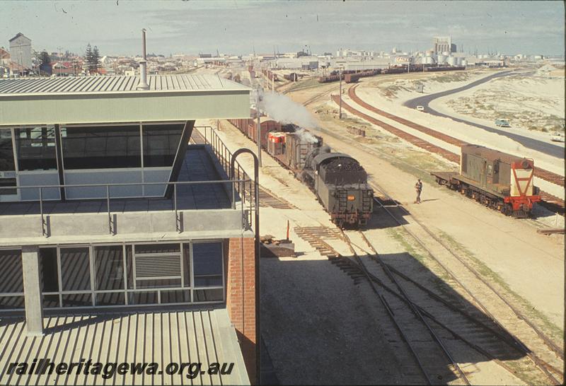 P09839
Leighton yard, control tower, North Fremantle signal box in distance, PMR class 729 in distance approaching turntable. PMR class 715 shunting train, Y class with shunters float, standard gauge sidings under construction. ER line.
