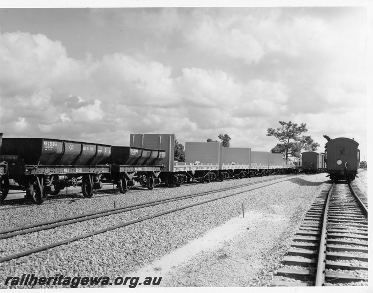 P10242
Ex Commonwealth Railways (CR) four wheel ballast hoppers coupled to four WSF standard gauge flat wagons with end bulkheads, narrow gauge rolling stock on adjacent tracks
