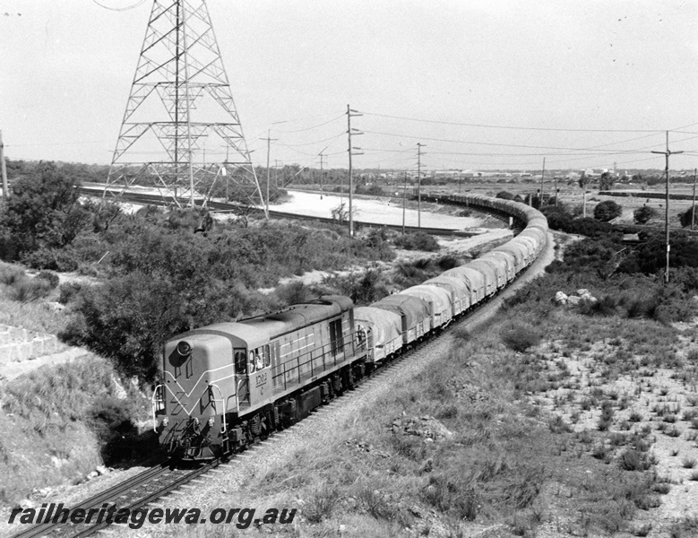 P10321
C class 1702 with a train of wagons all covered with tarpaulins departing Kwinana, elevated view of the train taken from the Rockingham Road over bridge.
