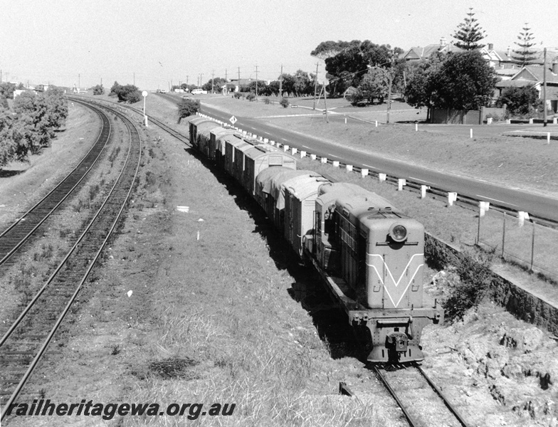 P10351
Y class 1108 Westrail Orange, long end leading running on freight only line between Leighton and Cottesloe. Short mixed freight mainly wheat covered wagons. Up and down suburban lines on left of train.

