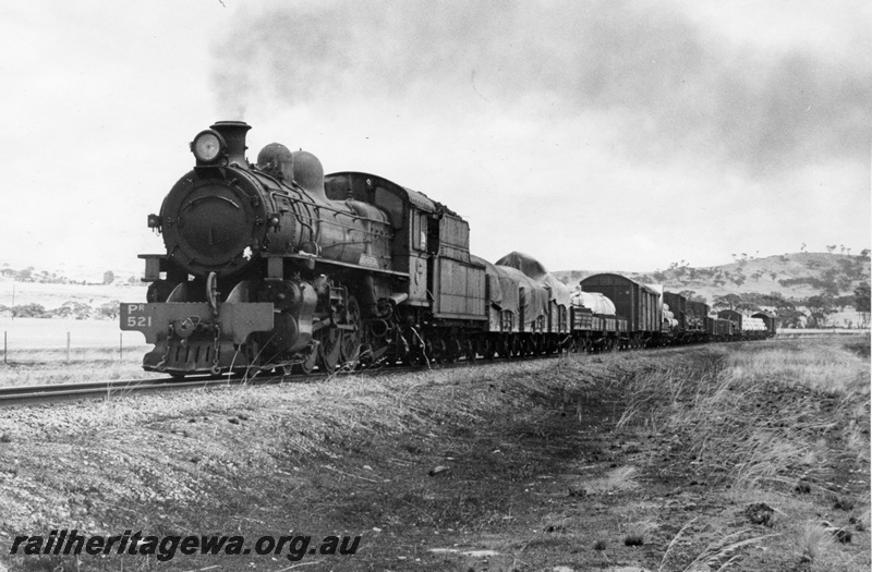P10353
PR class 521. On freight train of mixed wagons in open country, three quarter view light smoke plume. 
