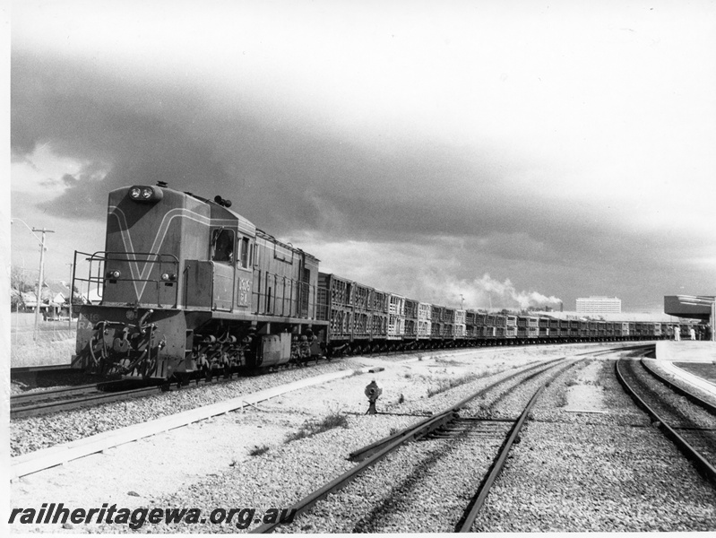 P10358
RA class 1916 . Green with Red and Yellow Stripes, short end leading with train CXB and CXA class of livestock wagons passing East Perth Terminal bound for Midland, portion of passenger terminal visible together with main line and loop with catch point indicator visible in foreground.
