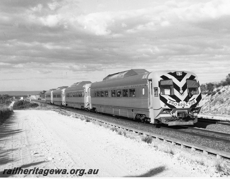 P10452
Prospector 4 car set travelling through after crossing a freight train. Front view of leading car displays black striping.
