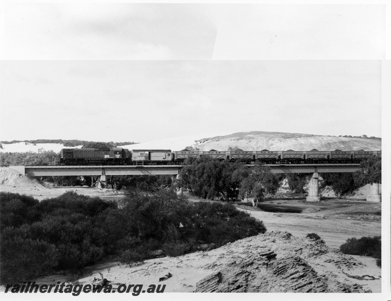 P10477
AB class 1536 diesel locomotive hauling 28 QW class container wagons on the Irwin River bridge on the Eneabba railway. The bridge is of concrete construction and the wagons were former W class steam locomotive tender chassis.
