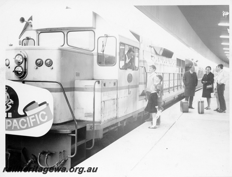 P10589
L class 258 standard gauge diesel locomotive at the head of the Indian Pacific at Perth Terminal. Driver talking to children as older people are standing background.
