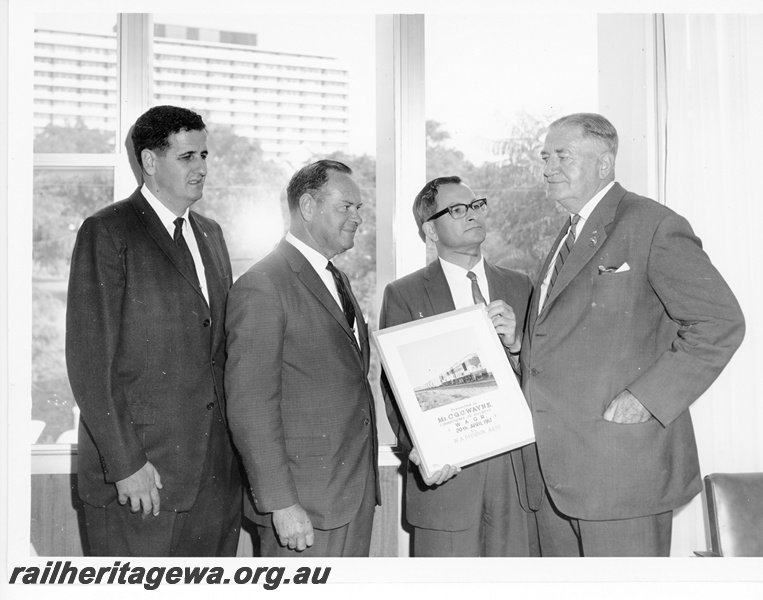 P10591
Noel Zeplin, Stan Bishop and Don Tyler representing the Australian Railway Historical Society, presenting the retiring Commissioner of Railways, Mr. C. G. C. Wayne, with a framed photograph of the inaugural winner of the C. G. C. Wayne Photo Competition. The photograph taken by Allan Tilley depicts K class 203 and K class 207 hauling an empty grain train near Millendon on the 25th of February, 1967.

