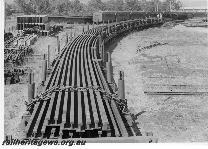 P10604
Welded rails loaded on a rake of specially fitted flat top wagons awaiting transport. Midland Workshops, Note former 'dog box' style coaches at rear left.
