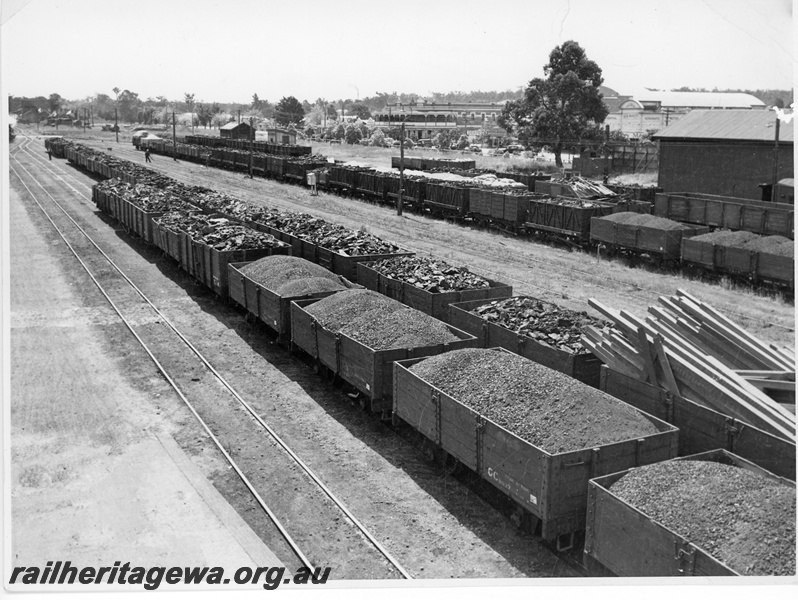 P10799
Yard, sidings, rakes of goods wagons laden with coal, timber and other materials, workers, trackside sheds, hotel and shops in background, Collie, BN line, overall view from elevated position
