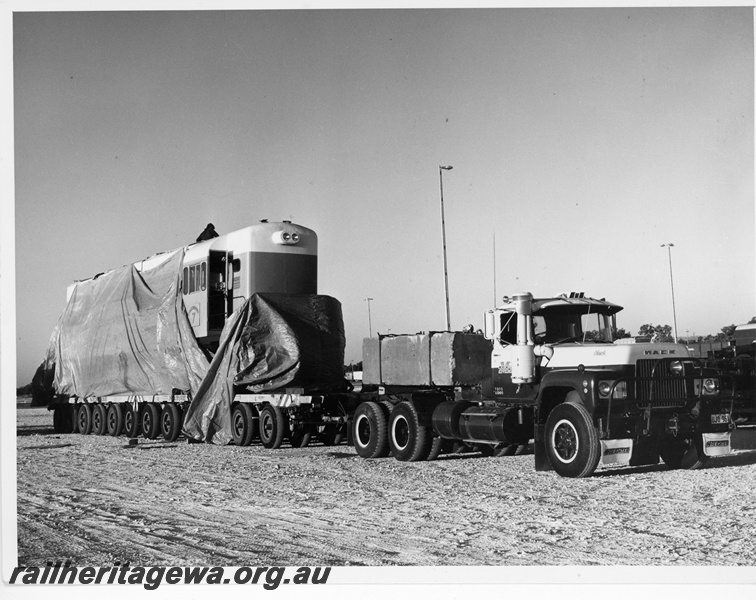 P10894
Goldsworthy Mining (GML) A class 7 at Forrestfield being prepared for a 1706 km road journey to Port Hedland. This being the final section of its delivery trip from Queensland. The locomotive was wrapped in plastic for the road trip. 
