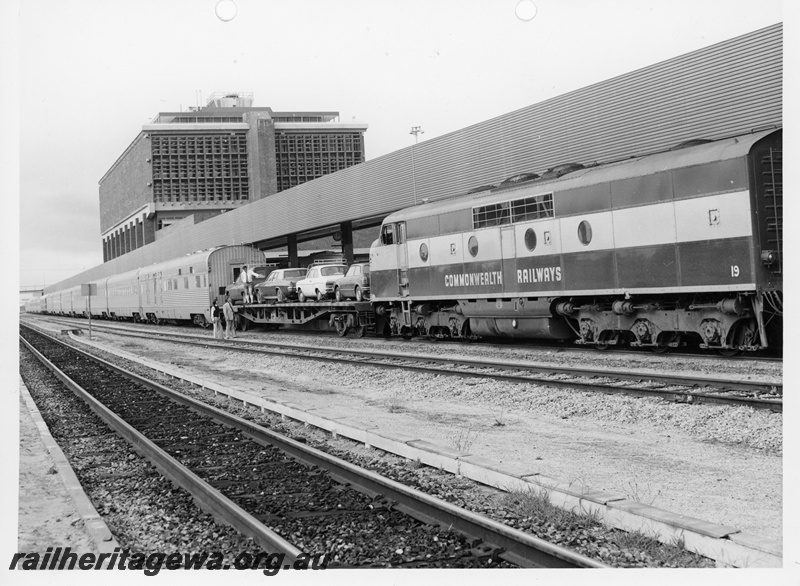 P10917
Commonwealth Railways (CR) GM class 19 diesel locomotive about to shunt a flat top wagon loaded with cars at East Perth Terminal. Good side view of locomotive and wagon,
