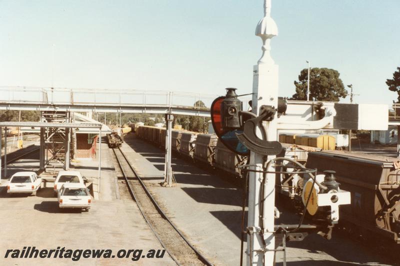 P11059
Signal, footbridge, station building, yard, line of wagons, Narrogin, GSR line, elevated view looking south showing tracks on the west side of the yard.
