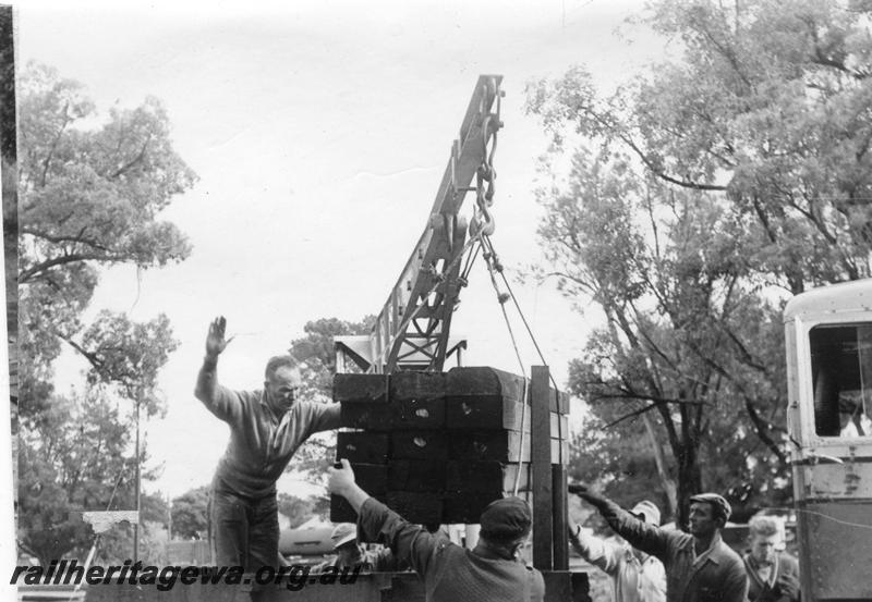 P12030
8 of 12 images of the construction of the Kwinana to Jarrahdale railway. (ref: The Railway Institute Magazine, July 1963).view shows the loading of a pack of sleeper by a crane onto a wagon.
