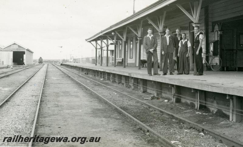 P12045
Station building, goods shed, station staff lined up on the platform, L to R, K. Ashby (Afternoon Station Master), R. Doughty (Night Station Master), W. Sobejko (Safeworking Porter), J. Orr (Station Master), L. Stephens (Junior Worker), trackside view, Southern Cross,  EGR line.
