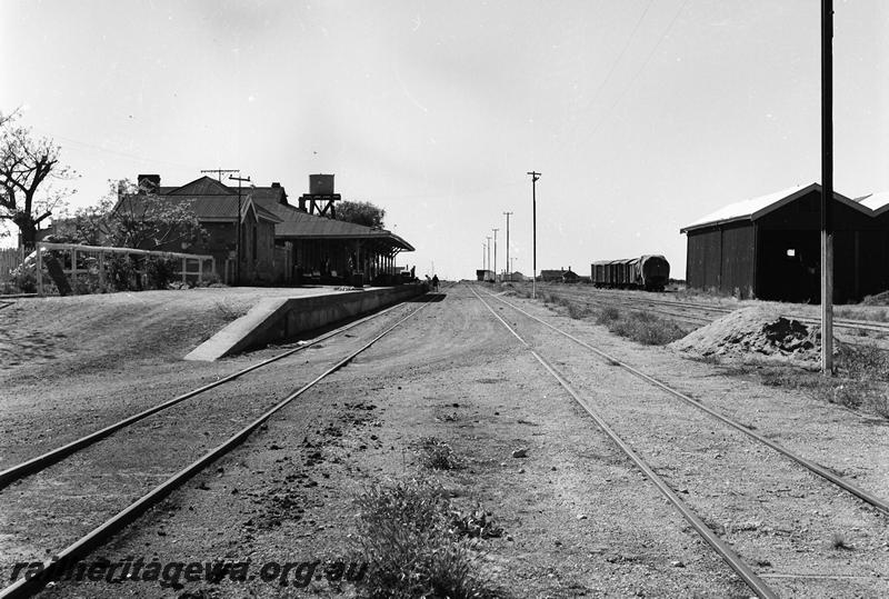 P12762
Station buildings, goods shed, water tower on stone (masonry) base in the far background, Yalgoo, NR line, view down the track.

