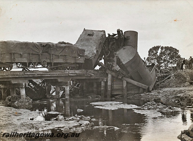 P12924
3 of 8 images of a derailment at Dumberning, BN line, RA class bogie open wagon on a small trestle bridge, other wagons including a J class and a JA class water tank derailed and off the tracks. Date of derailment 14/3/1934
