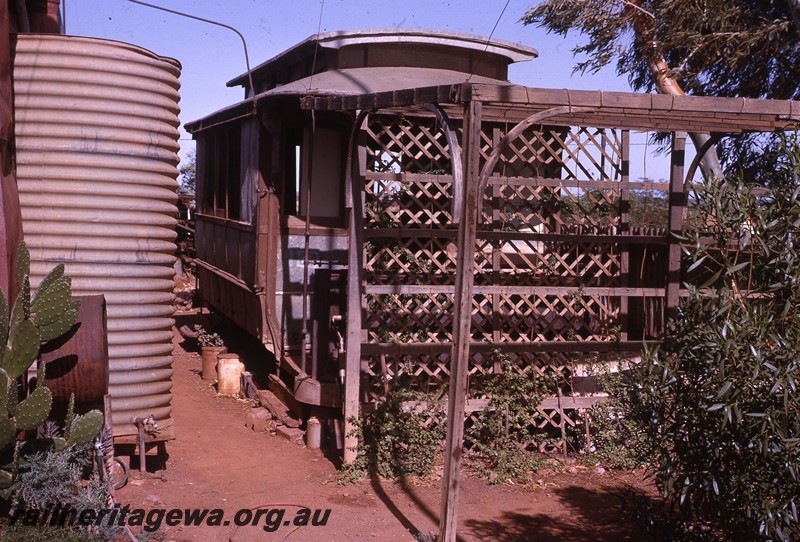 P13076
Tram body, Leonora, abandoned in a back yard, formerly from the Leonora to Gwalia tramway, front on view 
