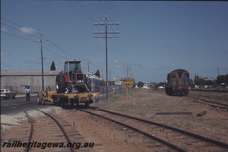 P13191
Tractor moving a four wheel flat wagon with a tractor on board across Whately Crescent from the Massey Ferguson plant in Maylands, F class 42 waiting in the yard to receive the wagons.
