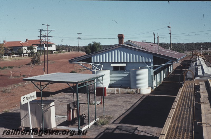 P13199
Lever frame with canopy, station building, Mullewa, NR line, elevated end view of structures. 
