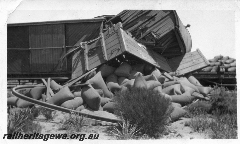 P13502
2 of 5 views of a derailment, date and location Unknown, view shows derailed and smashed wagons with bagged wheat strewn on the ground.
