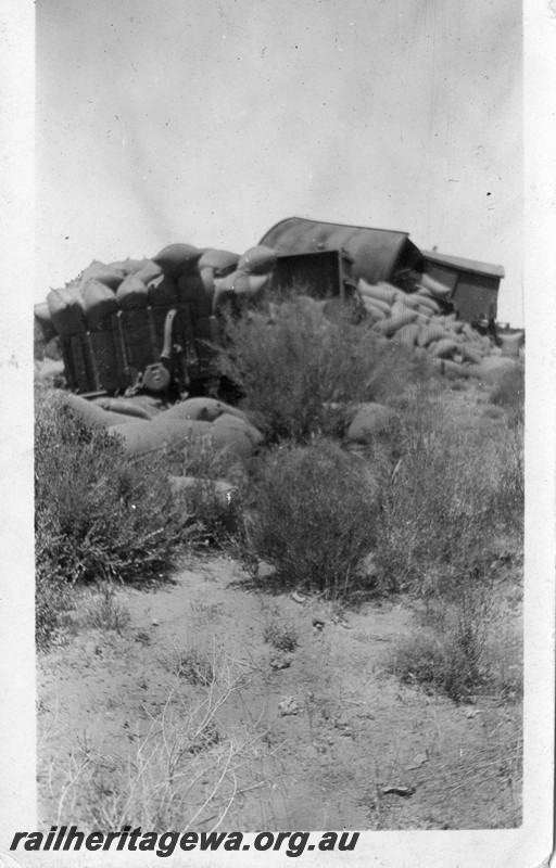 P13503
3 of 5 views of a derailment, date and location Unknown, view shows derailed and smashed wagons with bagged wheat strewn on the ground.
