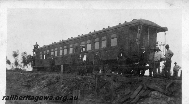 P13526
3 of 4 views of derailment of a platform ended carriage, date and location Unknown, side and end view, workers standing around.
