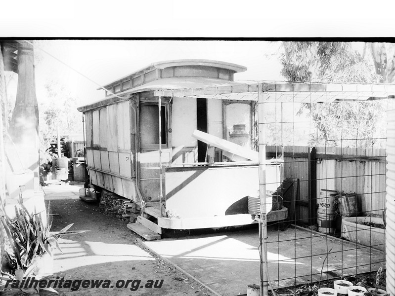 P13868
Tram body, Leonora, abandoned in a back yard, formerly from the Leonora to Gwalia tramway, front and side view 
