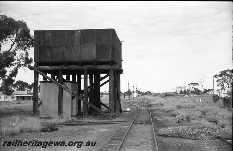 P14062
Water tower, 25,000 gallon cast iron water tank, shed incorporated in the tank stand, cheese knob, length runner's retreat, loading platform, loading crane, view down yard, Widgiemooltha, CE line.
