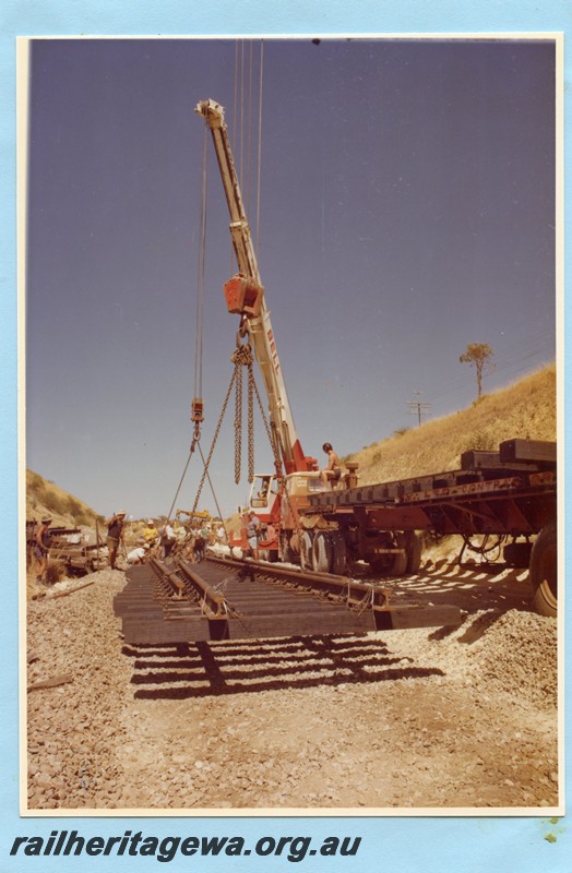 P14104
1 of 3 Trackwork within a cutting using a Bell Bros. crane to lift panels of track into position.
