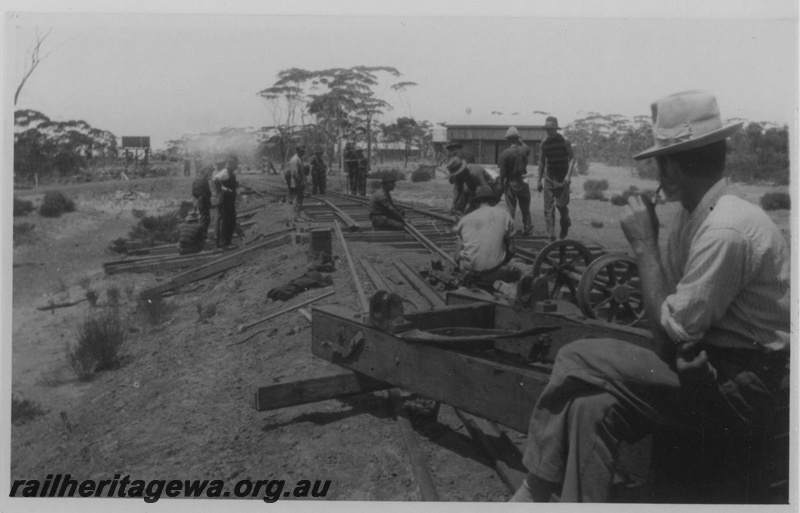 P14503
Track layers working on construction of the line joining Salmon Gums to Esperance, Salmon Gums, water tower in the background, CE line, view along the line. c1927
